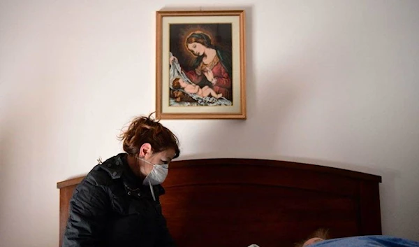 A woman talks to her 80-year-old mother, who is in bed with potential symptoms of COVID-19.(Piero Cruciatti/AFP/Getty Images)