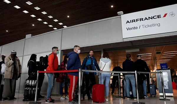 Travelers wear protective face masks at the Air France ticketing desk at Paris Charles de Gaulle Airport outside Paris on March 12 (Source: Reuters)