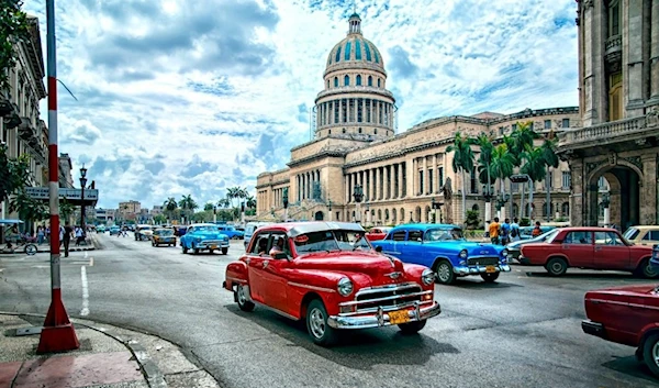 Vehicles in Havana, Cuba drive past The National Capitol Building (El Capitolio)