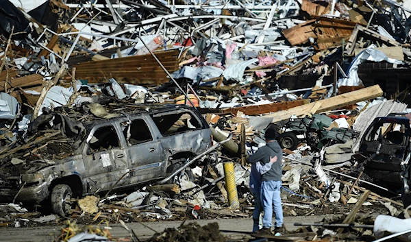 People embrace as tornado damage is seen after extreme weather hit the region December 12, 2021, in Mayfield, Kentucky (AFP)