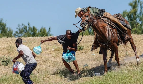 A Border Patrol agent grabbing a migrant by the shirt