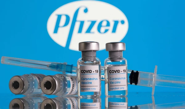 Vials labelled "COVID-19 Coronavirus Vaccine" and sryinge are seen in front of displayed Pfizer logo in this illustration taken, February 9, 2021 (Credit: Reuters)