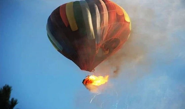 The multi-colored balloon skirted the top of the power lines.