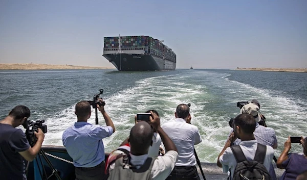 Reporters photographing “Ever Given” ship as it sails the Suez Canal in Egypt on 5 July 2021 (AFP)