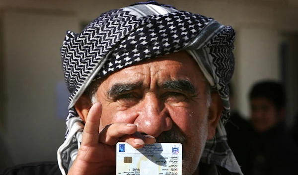 An Iraqi voter holding his voting card