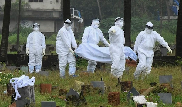 People wearing protective suits, carrying the body of the 12-year old boy who died of the virus