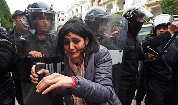 A protester is seen in front of police officers standing guard during a demonstration against the government and price hikes in Tunis, Tunisia, 9 January 2018, FETHI BELAID/AFP/Getty Images