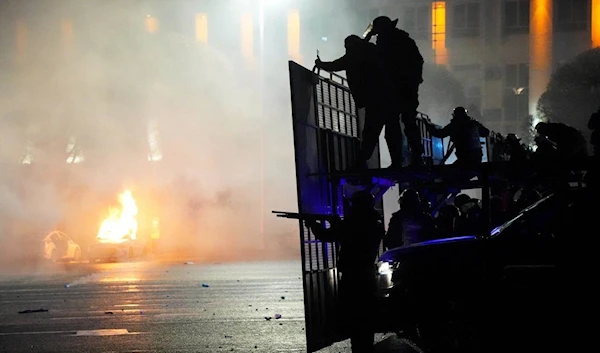 A police car on fire as riot police prepare to stop protesters in the center of Almaty, Kazakhstan, January 5, 2022 (AP)