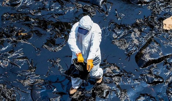 A volunteer cleans - what he can - of the environmental impact of the Repsol oil spill grows off the coast of Peru (Municipality of Ventanilla)