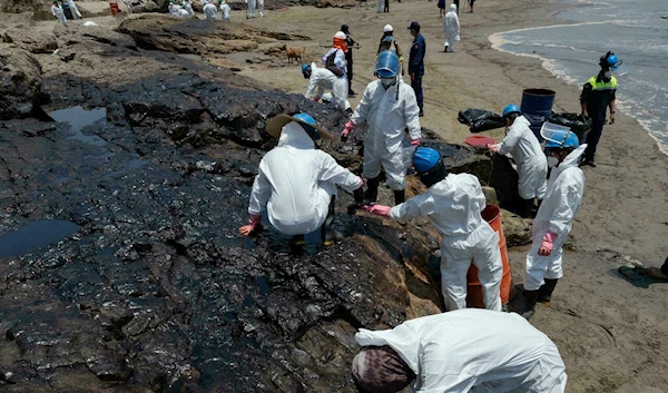 Workers on a Peruvian beach clean up an oil spill caused by abnormal waves triggered by a massive underwater volcanic eruption in Tonga (AFP)