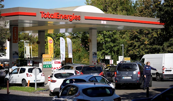 A police officer directs cars as drivers line up in a gas station in Paris, Tuesday, Oct.11, 2022 (AP Photo/Christophe Ena)