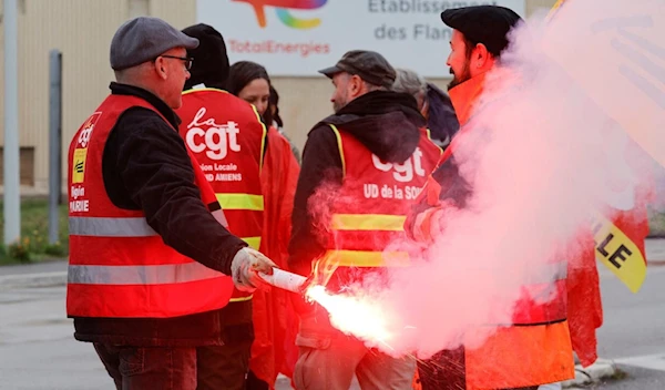 Striking workers use a red flare in front of Total gasoline tanks, October 13, 2022 (Reuters)