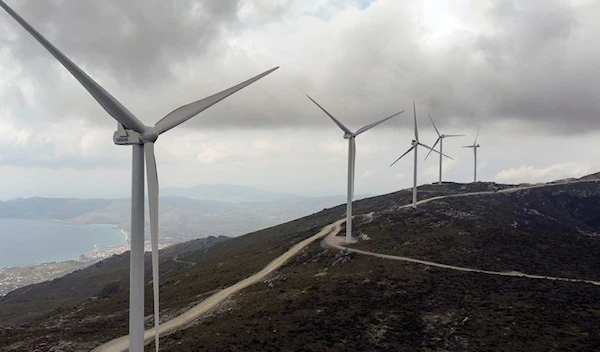 Wind turbines are seen on a mountain as the town of Karystos, Greece. (REUTERS)