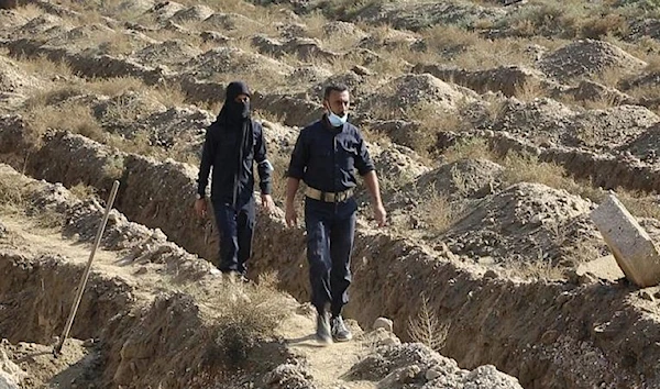 File Photo: Syrian workers in Raqqa walk on a mass grave believed to contain the bodies of many hundreds of civilians. (Source: AP)