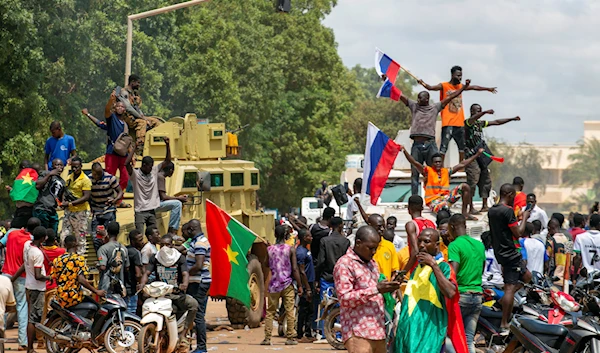 Supporters of Capt. Ibrahim Traore cheer with Russian flags in the streets of Ouagadougou, Burkina Faso, Sunday, Oct. 2, 2022 (AP Photo/Kilaye Bationo)