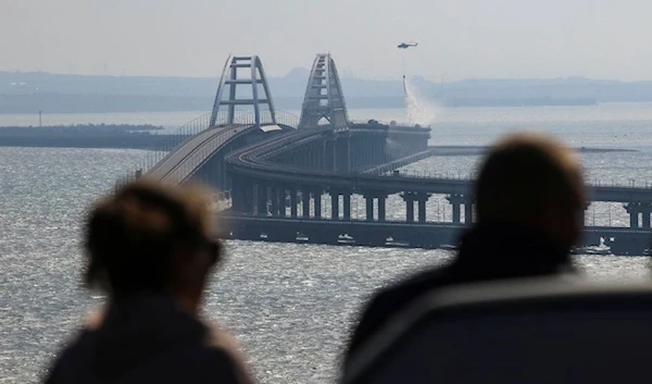 People watch fuel tanks ablaze on the Kerch bridge in the Kerch Strait, Crimea, October 8, 2022. (Reuters)