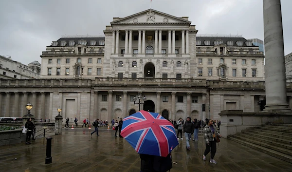 A woman with an umbrella stands in front of the Bank of England, at the financial district in London, Thursday, Nov. 3, 2022 (AP Photo/Kin Cheung)