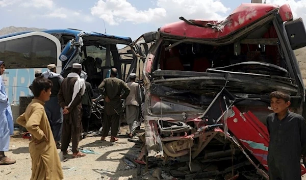 People stand near damaged buses after a deadly accident on the Kabul-Kandahar highway (Archive)