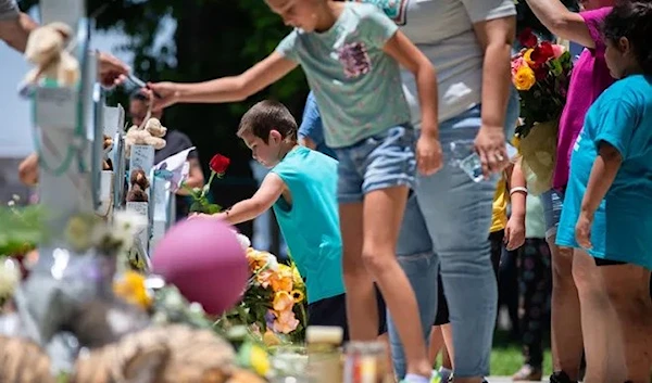 Mourners place flowers, candles and tokens on crosses for each of the Robb Elementary School shooting victims at a memorial put up in the Uvalde Town Square, May 27, 2022 (American-Statesman)