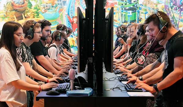 Players check the latest video games in the fair halls at the Gamescom computer gaming fair in Cologne, Germany, Thursday, Aug. 25, 2022 (AP Photo/Martin Meissner)