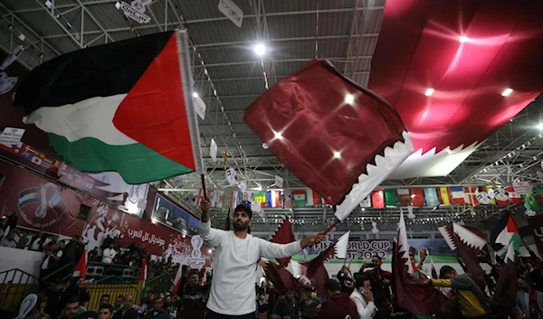 A football fan waving the Palestinian and Qatari flags at the Qatar World Cup 2022