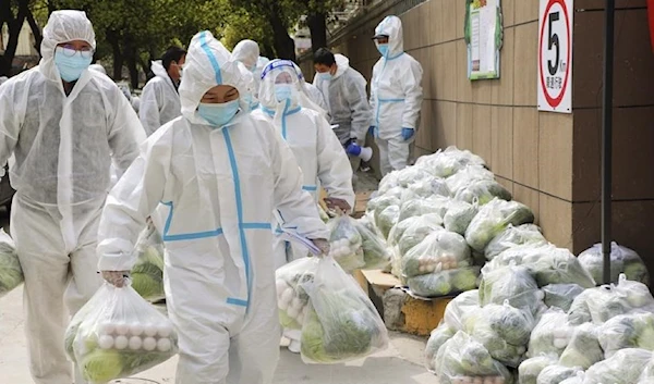 In this photo released by Xinhua News Agency, volunteers carry daily necessities for residents in Fengxian District in eastern China's Shanghai. (AP)