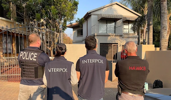 The Interpol and FBI in front of one of the residences during the operation (Interpol)