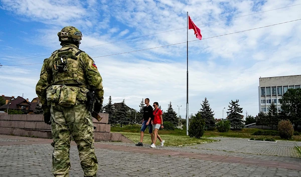 A young couple walks past a Russian soldier guarding an area at the Alley of Glory exploits of the heroes - natives of the Kherson region (AP Photo, File)