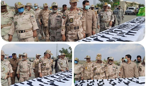 The Iranian border guard standing behind a table showing the seized weapons and ammunition