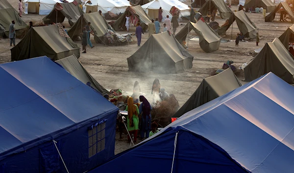 Victims of heavy flooding from monsoon rains take refuge as they prepare tea at a temporary tent housing camp organized by the UN Refugee Agency (UNHCR), in Sukkur, Pakistan, Sept. 10, 2022 (AP Photo/Fareed Khan, File)