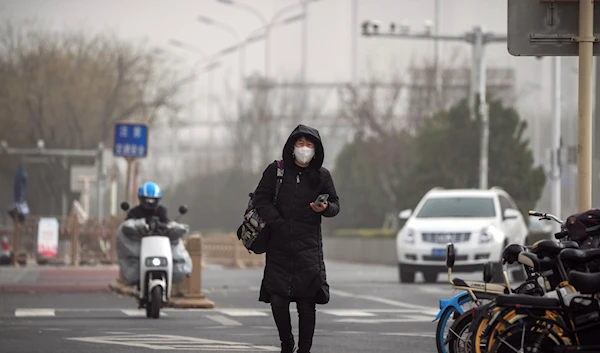 A woman wearing a face mask walks on a street in Beijing, Monday, Dec. 12, 2022, as capital city is hit by sandstorm (AP Photo/Andy Wong)