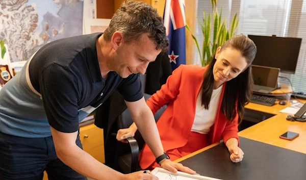 David Seymour and Jacinda Ardern sign the printout of Hansard they plan to auction off for charity. Source: ACT Party