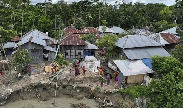 Families live along an eroded embankment by the Meghna River in Bangladesh (AP)