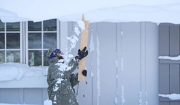 A man clears snow from his roof in Amherst, N.Y., on Dec. 25. (Reuters)