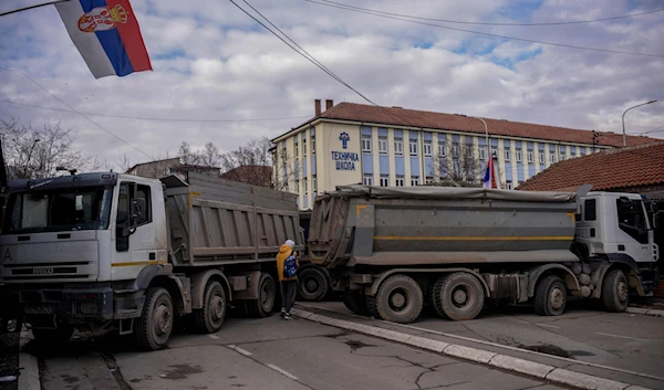 A pedestrian walks past a road barricade set up in the divided town of Mitrovica, Kosovo, December 28, 2022 (AFP Photo)