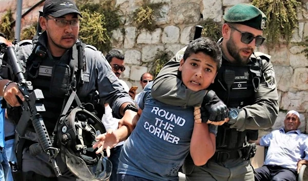 Israeli officers aggressively arrest a Palestinian boy. (AFP)