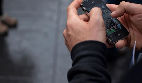 A man uses her Apple iPhone 4 smartphone. (REUTERS)