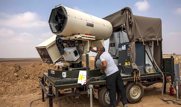 An Israeli occupation police officer demonstrates a laser defense system designed to intercept explosives-laden balloons launched from Gaza, Aug. 30, 2020 (AP Photo/Tsafrir Abayov, File)