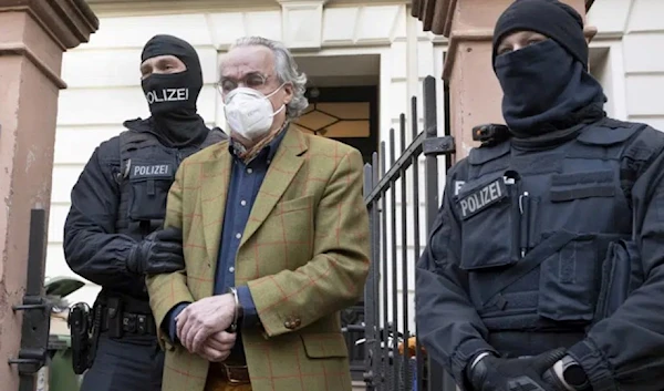 Masked police officers lead Heinrich XIII Prince Reuss, center, to a police vehicle during a raid against so-called 'Reich Citizens' movement in Frankfurt