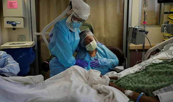 An American woman weeping while sitting next to her dying husband, and is comforted by a nurse in St. Jude Medical Center's COVID-19 unit in Fullerton, California, Friday, July 31, 2020 (AP)