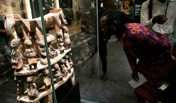 A man looks at Cana throne, a sacred town looted by French colonial soldiers displayed during an exhibition of returned seized Benin artefacts at the presidency in Benin's capital Cotonou, February 18, 2022 (AFP)