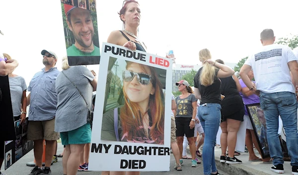 A protestor holds a picture of her dead daughter, who had used OxyContin