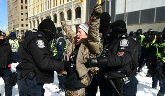 A protester sings the national anthem as they are taken into custody by police officers in Ottawa. Photograph: Justin Tang/AP