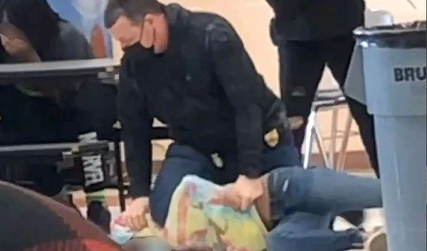 An off-duty police officer is shown kneeling on the 12-year-old student's neck on March 4, 202