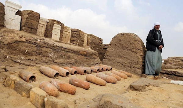 An archaeologist looks on after working outside a newly discovered tombs at the Saqqara area, in Giza, Egypt, March 19, 2022 (Reuters)