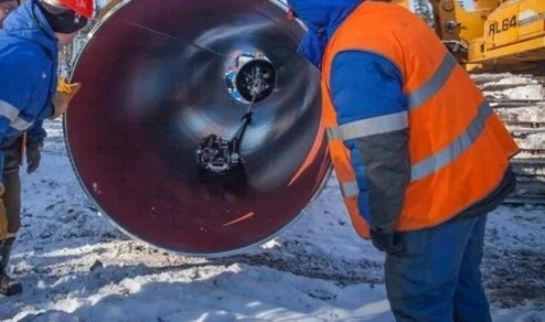 A worker adjusts a Gazprom branded end cap on a section of pipework, Russia. (Bloomberg)