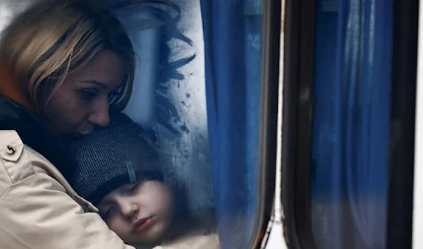 A woman and her son are seen through a bus window as they arrive at a temporary accommodation centre. (Reuters)