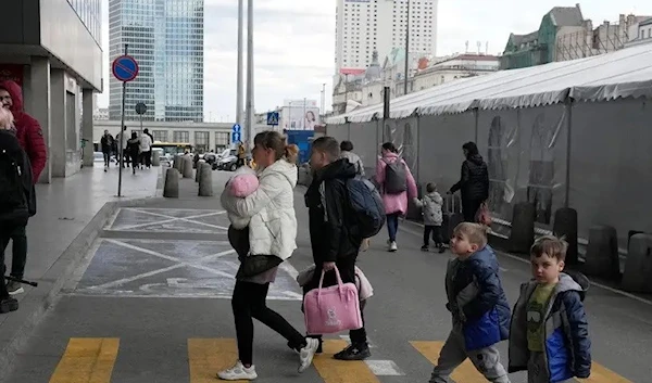 A refugee woman with children walk to the central train station in Warsaw on April 7, 2022. (AP)