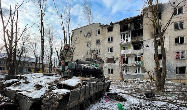 A Donbass republics soldier standing over an abandoned Ukrainian T-64 BV tank