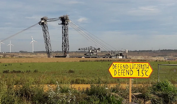 A small earth wall separates the tiny village of Lutzerath from the enormous diggers operating in the lignite coal mines